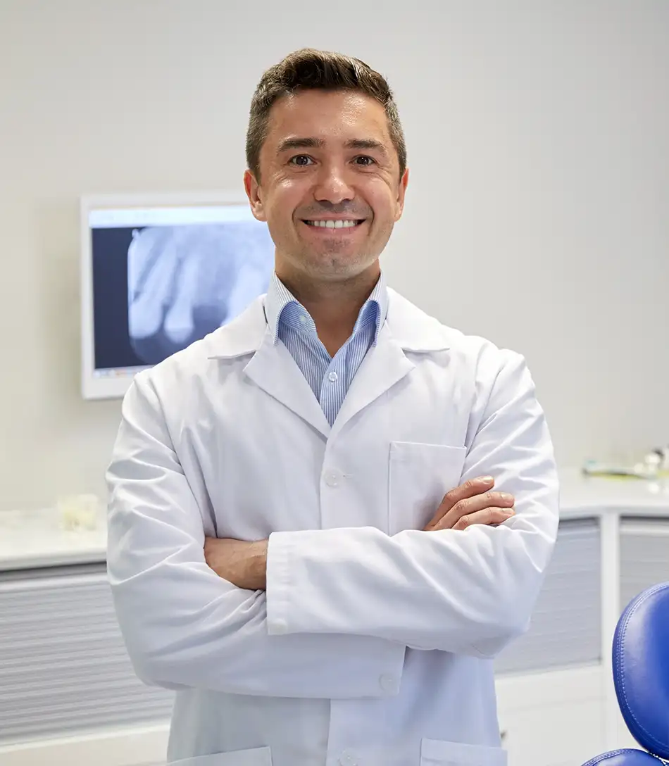 Dentist standing in his office smiling while looking at the camera