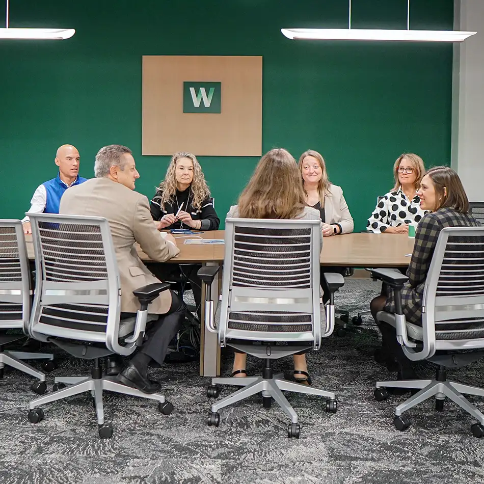 Walsh employees meeting in a large conference room, discussing how to best serve their clients
