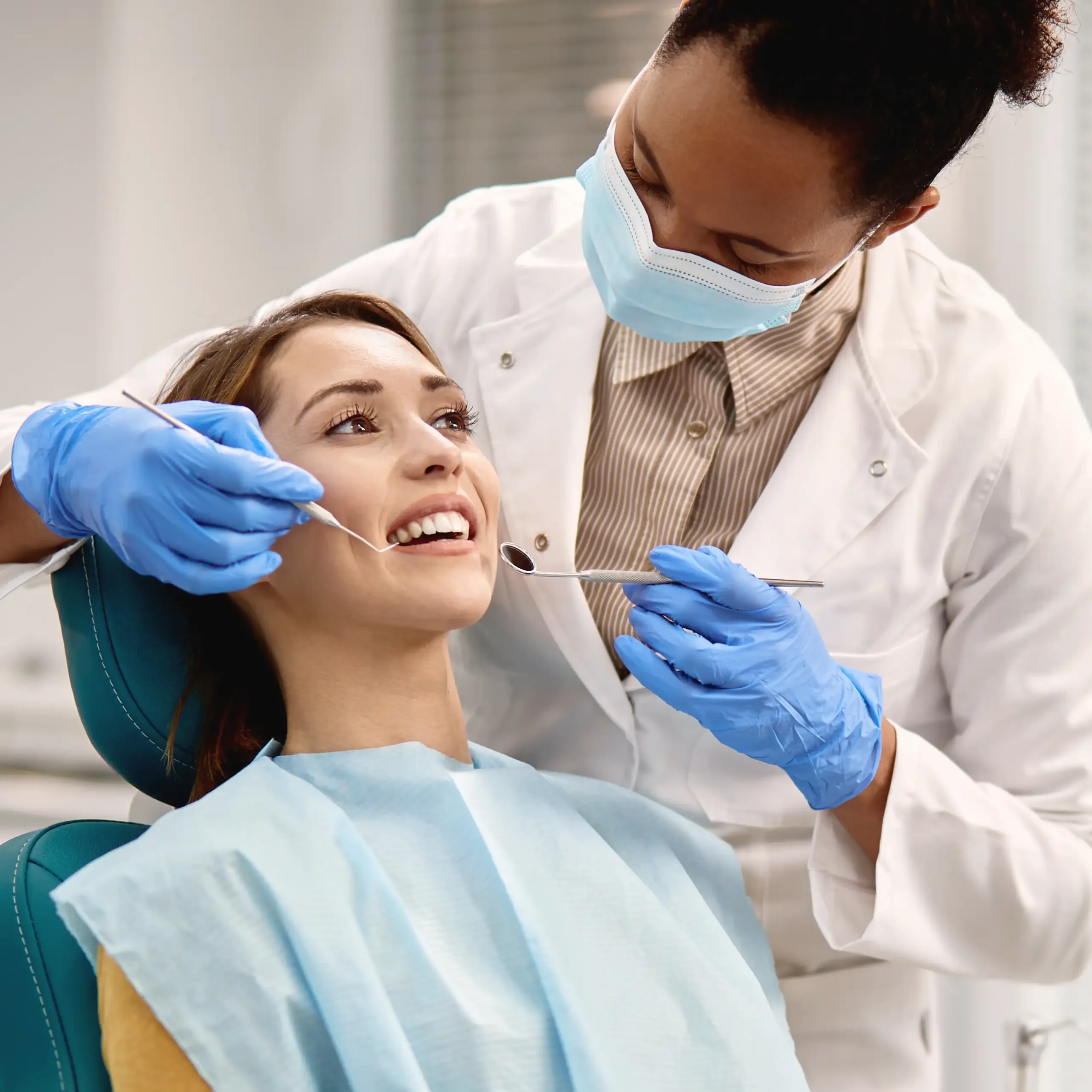 Female dental hygienist performing a routine dental checkup with a young female patient